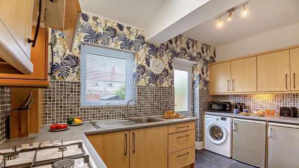A modern kitchen with a gas stove, sink, and washing machine. - 1 Bed in Old Colwyn (oc-r29472) (Hen Golwyn)