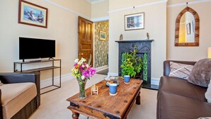 A living room with a television, a fireplace, a sofa, and a coffee table. - 1 Bed in Old Colwyn (oc-r29472) (Hen Golwyn)