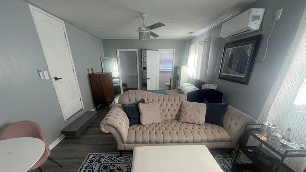 A living room with a beige sofa, a white ottoman, a patterned rug, a wooden chair, and a small table. - Charming 1-bedroom in-law suite with functional kitchen in pleasant Portsmouth (Portsmouth)