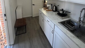 A compact kitchen with white cabinets, a marble countertop, a built-in sink, and a small stool. - Charming 1-bedroom in-law suite with functional kitchen in pleasant Portsmouth (Portsmouth)