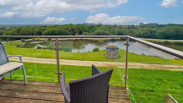 Une terrasse offrant une vue sur un canal, de la verdure et un paysage lointain.