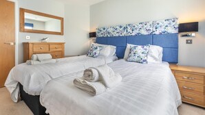 Un lit double avec une tête de lit, une table de chevet en bois, une commode et un miroir.