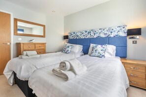 A double bed with a headboard, a wooden nightstand, a dresser, and a mirror. - 4 Bed in Winnards Perch (oc-t29558) (Winnard's Perch)