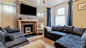 A living room with a fireplace, two sofas, a chair, and a television. - 6 Bed in Bridlington (oc-n29516) (Bridlington)