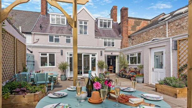 A patio with round tables set for dining, a bicycle, and a garden area with potted plants.