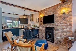 A modern kitchen with a large island, a dining area with bar stools, and a fireplace.