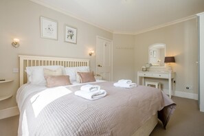 Een slaapkamer met een bed, nachtkastjes, een dressoir, een spiegel en wandlampen.