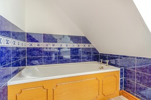 A bathroom with a bathtub, blue marble tiles, and wooden cabinets. - 2 Bed in Devils Bridge (oc-d29575) (Pontarfynach)