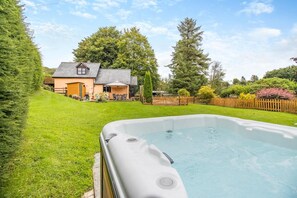 Un patio trasero con un jacuzzi, una casa y una valla de madera.