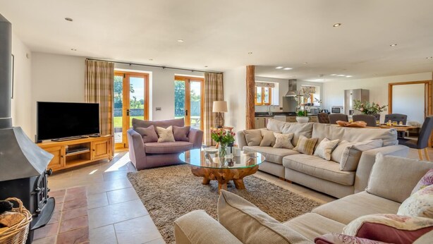 A spacious living room with a TV, sofas, a coffee table, and a fireplace. - 3 Bed in Lower Bodham (oc-p29593) (Bodham)