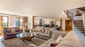 A spacious living room with a large sofa set, a glass coffee table, and a staircase leading to an upper level. - 3 Bed in Lower Bodham (oc-p29593) (Bodham)