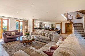A spacious living room with a large sofa set, a glass coffee table, and a staircase leading to an upper level. - 3 Bed in Lower Bodham (oc-p29593) (Bodham)