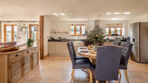 A spacious kitchen with a dining area, wooden cabinets, and a large window. - 3 Bed in Lower Bodham (oc-p29593) (Bodham)