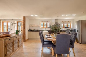 A spacious kitchen with a dining area, wooden cabinets, and a large window. - 3 Bed in Lower Bodham (oc-p29593) (Bodham)
