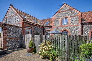 Ein Steinhaus mit Holzzaun, einem Blumentopf und einem Schotterweg.