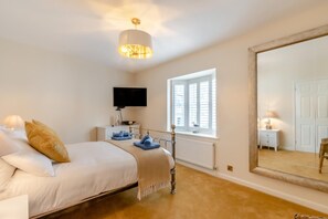 A bedroom with a bed, bedside table, lamp, and a large mirror. - 3 Bed in Tenby (oc-m29588) (Tenby)