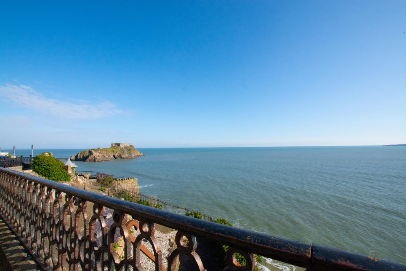 A coastal view with a fortified structure on a small island, a clear sky, and calm sea.