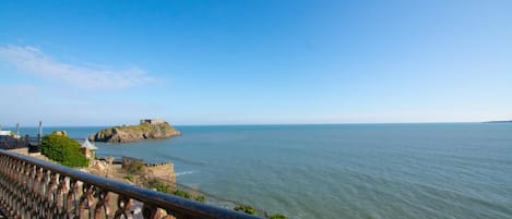 A coastal view with a fortified structure on a small island, a clear sky, and calm sea.