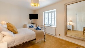 A bedroom with a bed, bedside table, lamp, and a large mirror. - 3 Bed in Tenby (oc-m29588) (Tenby)