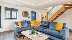 Una sala moderna con un sofá modular, una mesa de centro y una escalera.