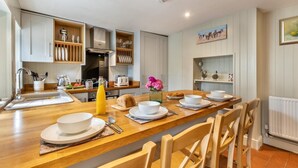 A modern kitchen with wooden countertops, a built-in oven, and a dining area with a long table set for four. - 2 Bed in Snettisham (oc-t29559) (Snettisham)