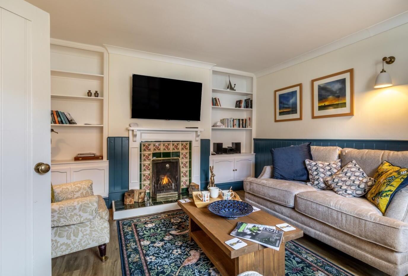 A cozy living room with a fireplace, a sofa, a coffee table, and a bookshelf.
