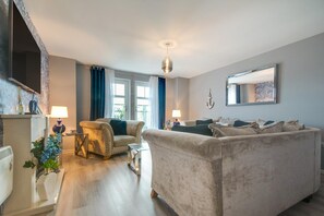 A modern living room with a sofa, armchairs, and a dining area. - 3 Bed in Whitby (oc-f29650) (Whitby)