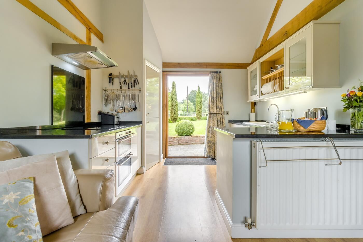 A modern kitchen with a dining area, wooden beams, and a view of the garden.