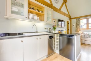 Une cuisine moderne avec des meubles blancs, des appareils en acier inoxydable et un plafond en bois.