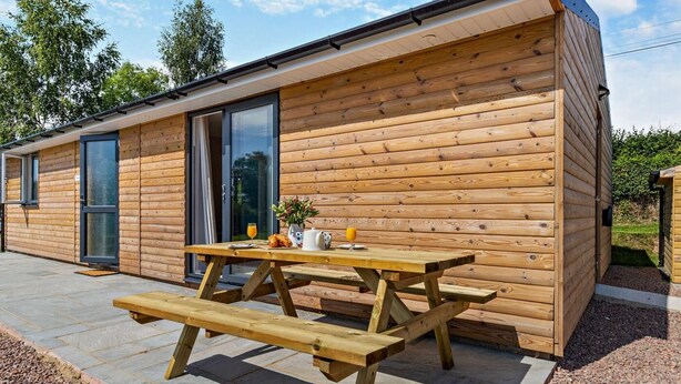 Une cabane en bois avec une table de pique-nique, une porte et une fenêtre.