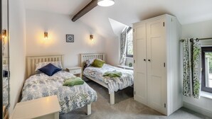 Ein Schlafzimmer mit zwei Betten, einem Kleiderschrank und einem Fenster mit Vorhängen.