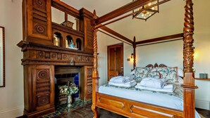 A four-poster bed with intricate woodwork, a fireplace with a tiled surround, and a mirror above the bed. - 1 Bed in Tollard Royal (oc-l29639) (Tollard Royal)