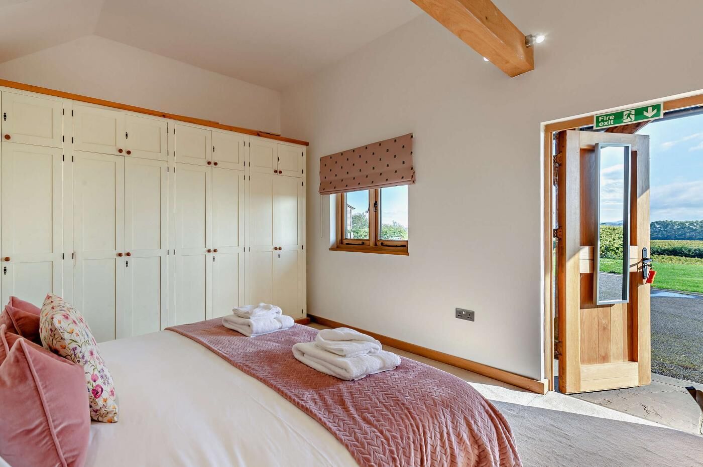 A bedroom with a bed, a wardrobe, a window, and a door leading outside.