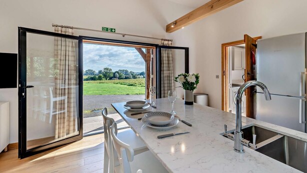 A modern kitchen with a large window, a dining area with a table set for two, and a view of a green landscape. - 1 Bed in Stone (oc-t29685) (Stone in Oxney)