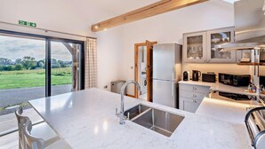 A modern kitchen with a large island, stainless steel appliances, and a view of the countryside. - 1 Bed in Stone (oc-t29685) (Stone in Oxney)
