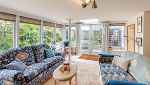 Ein großzügiges Wohnzimmer mit großem Fenster, einem Sofa, einem Couchtisch und einem Sessel.