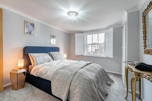 Un dormitorio con cama, lámparas de noche, una ventana y un espejo.