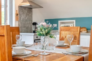 A dining table set with white bowls, wine glasses, and a vase of flowers.