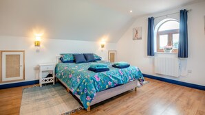 A bedroom with a bed, bedside tables, a window with curtains, and a radiator. - 1 Bed in Abbeydore (oc-l29485) (Abbey Dore)