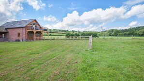 A brick building with a wooden balcony, a fenced field, and a clear sky. - 1 Bed in Abbeydore (oc-l29485) (Abbey Dore)