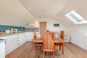 A modern kitchen with white cabinets, a wooden dining table, and a skylight. - 1 Bed in Abbeydore (oc-l29485) (Abbey Dore)