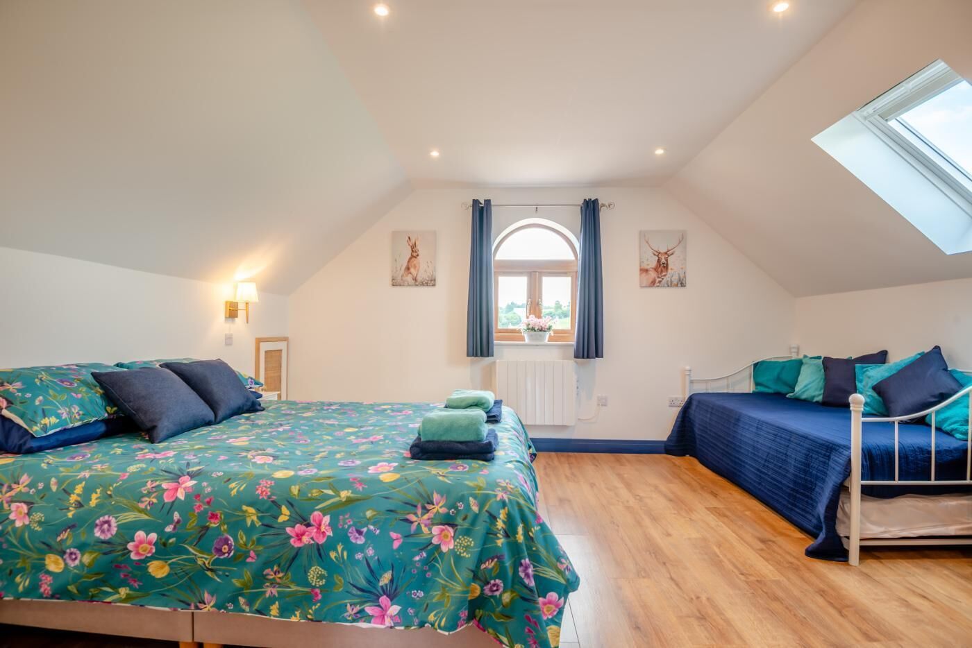 Een slaapkamer met twee bedden, dakraam, een raam met gordijnen, en kunstwerken aan de wanden.