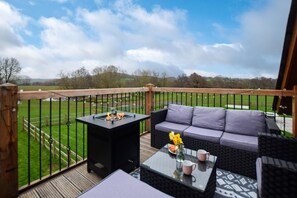 A balcony with a grill, a sofa, and a table with a vase and mugs.