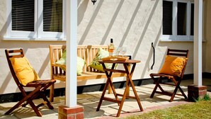 Een terras met twee houten stoelen, een tafeltje en een bank.