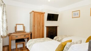 Een slaapkamer met twee bedden, een houten bureau, een televisie en een open haard.