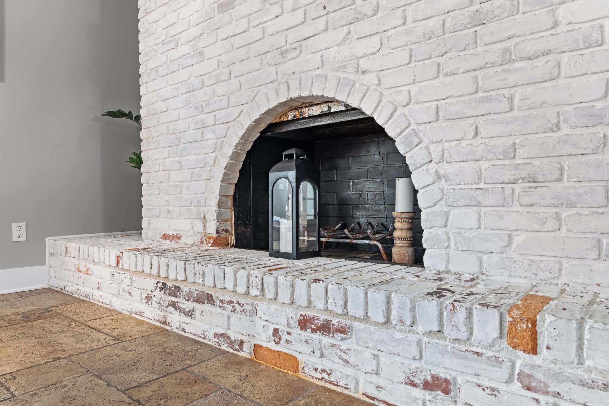 A white brick fireplace with a modern glass door, a built-in log storage area, and a simple, clean design.