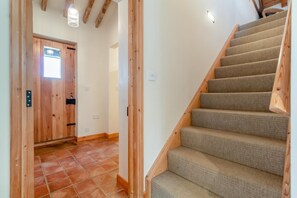 Eine Treppe mit Holzwangen und Teppichstufen, die zu einem Raum mit Holztür und Fenster führt.