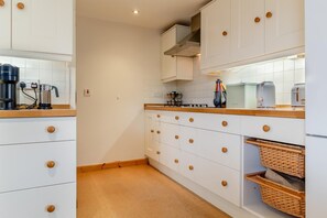 Eine Küche mit weißen Schränken, Holzgriffen, einer Kaffeemaschine und einem Toaster.