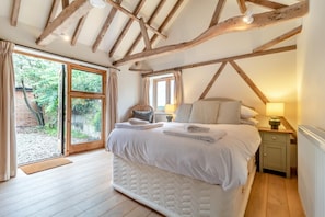 A bedroom with a large bed, wooden beams, a window, and a nightstand. - 3 Bed in Frostenden (oc-g29705) (Frostenden)