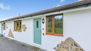 Un bâtiment blanc agrémenté de détails en pierre, avec une porte verte et de nombreuses fenêtres.